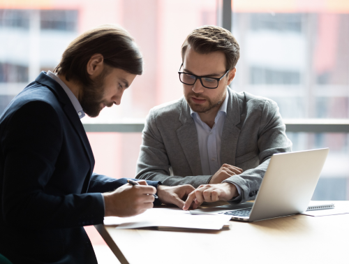 Two men at a desk looking over a document together, representing Settlement Agreements.