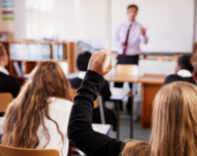 Female student raising hand to ask question in classroom.