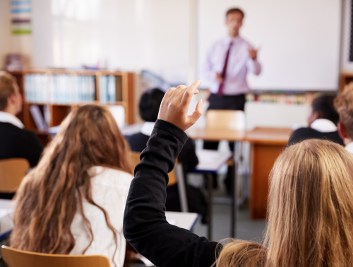 Female student raising hand to ask question in classroom.