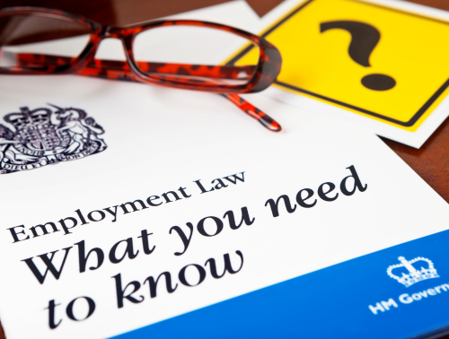 Employment Law guide sitting on a desk alongside a pair of reading glasses and a yellow card featuring a question mark.